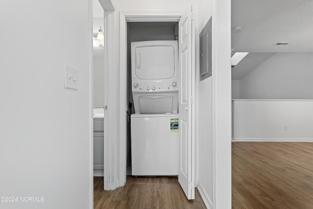 washroom featuring dark hardwood / wood-style flooring, a textured ceiling, and stacked washing maching and dryer