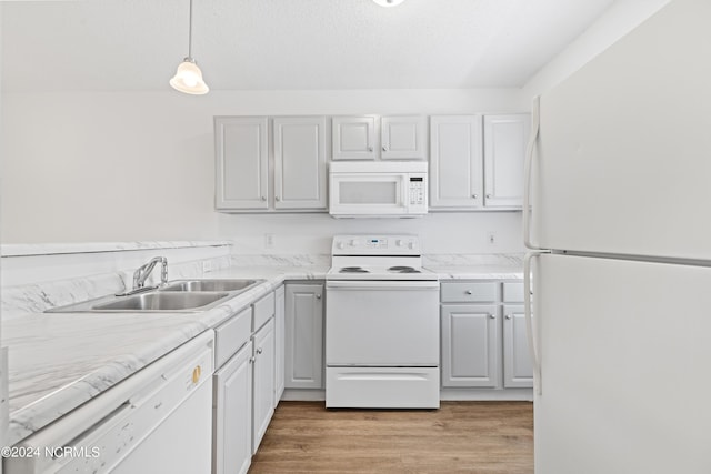 kitchen with pendant lighting, sink, white appliances, white cabinets, and light wood-type flooring