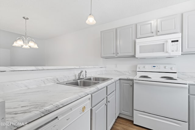 kitchen featuring sink, an inviting chandelier, hanging light fixtures, dark hardwood / wood-style flooring, and white appliances