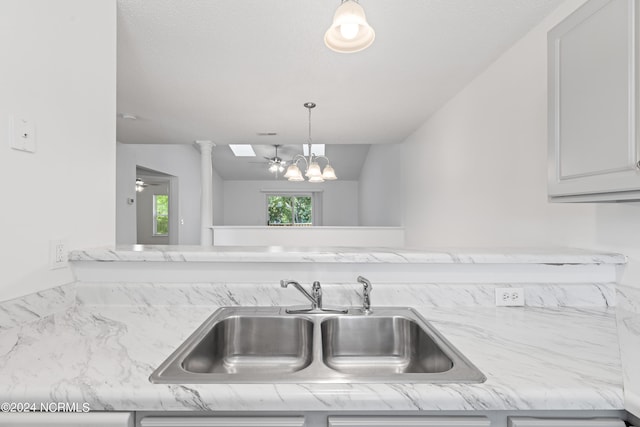 interior details featuring sink, white cabinets, an inviting chandelier, and decorative light fixtures