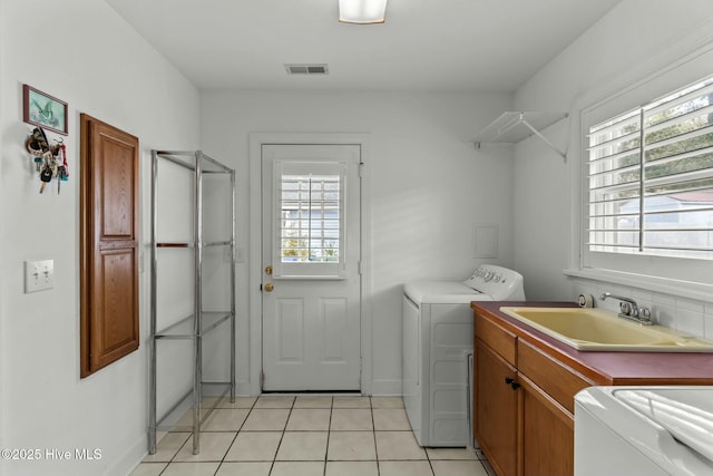 laundry room with cabinets, sink, light tile patterned floors, and washer and clothes dryer