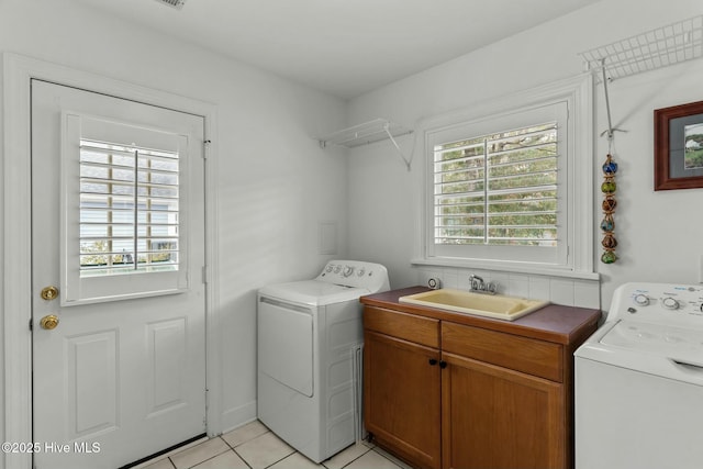 laundry area featuring sink, light tile patterned floors, cabinets, and independent washer and dryer