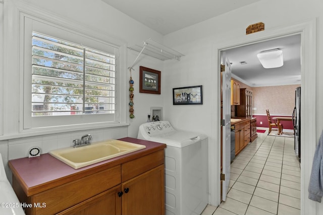 laundry room featuring sink, cabinets, ornamental molding, light tile patterned floors, and washer and clothes dryer