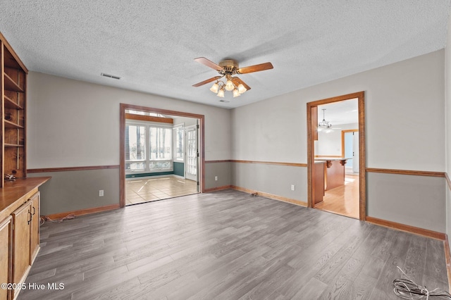 spare room with ceiling fan, a textured ceiling, and light wood-type flooring