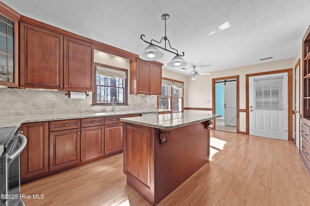 kitchen featuring a kitchen island, a barn door, hanging light fixtures, and light hardwood / wood-style flooring