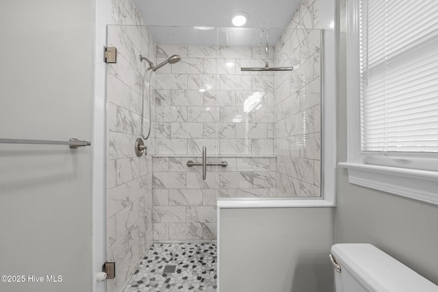 bathroom featuring toilet and a shower with shower door