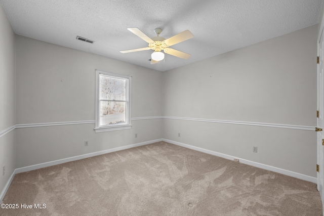 carpeted spare room featuring ceiling fan and a textured ceiling