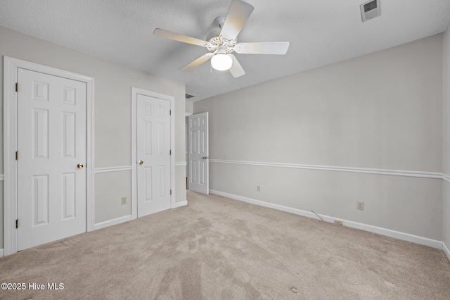 unfurnished bedroom featuring ceiling fan, light colored carpet, and a textured ceiling