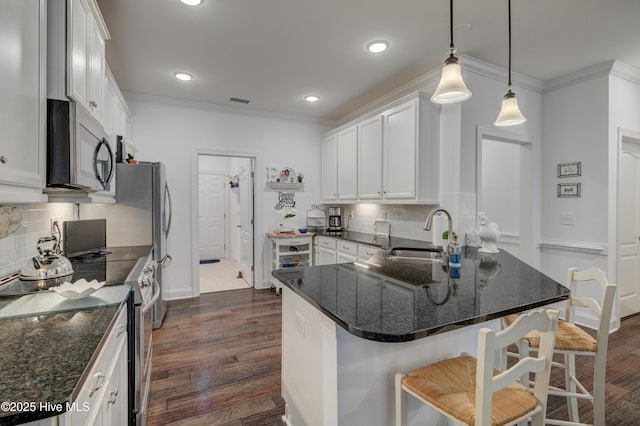 kitchen featuring white cabinetry, sink, a kitchen breakfast bar, hanging light fixtures, and stainless steel appliances