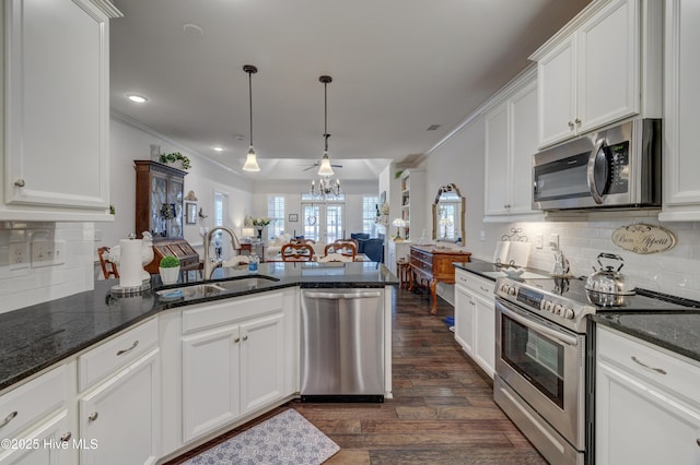 kitchen featuring sink, white cabinetry, ornamental molding, appliances with stainless steel finishes, and pendant lighting