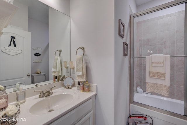 full bathroom featuring vanity, shower / bath combination with glass door, and toilet