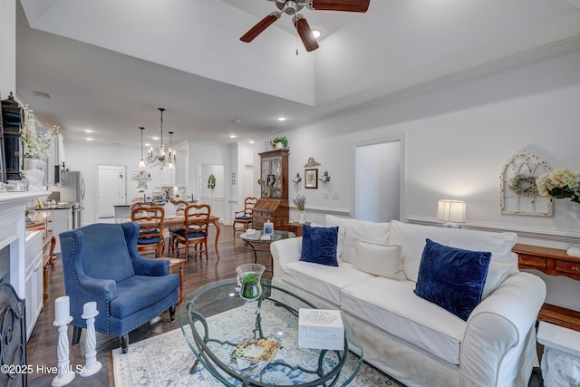 living room with ceiling fan with notable chandelier, dark wood-type flooring, and a towering ceiling