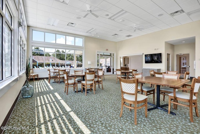 dining area featuring a drop ceiling, a towering ceiling, ceiling fan, and carpet