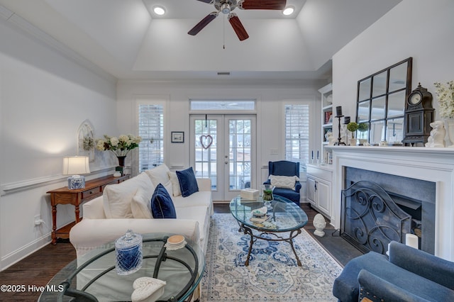 living room featuring ceiling fan, dark hardwood / wood-style floors, a tray ceiling, ornamental molding, and french doors