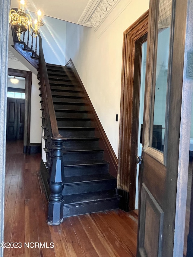 staircase featuring hardwood / wood-style floors and a notable chandelier