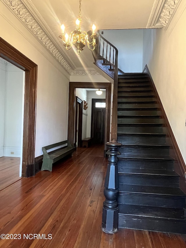 stairway with an inviting chandelier, crown molding, and wood-type flooring