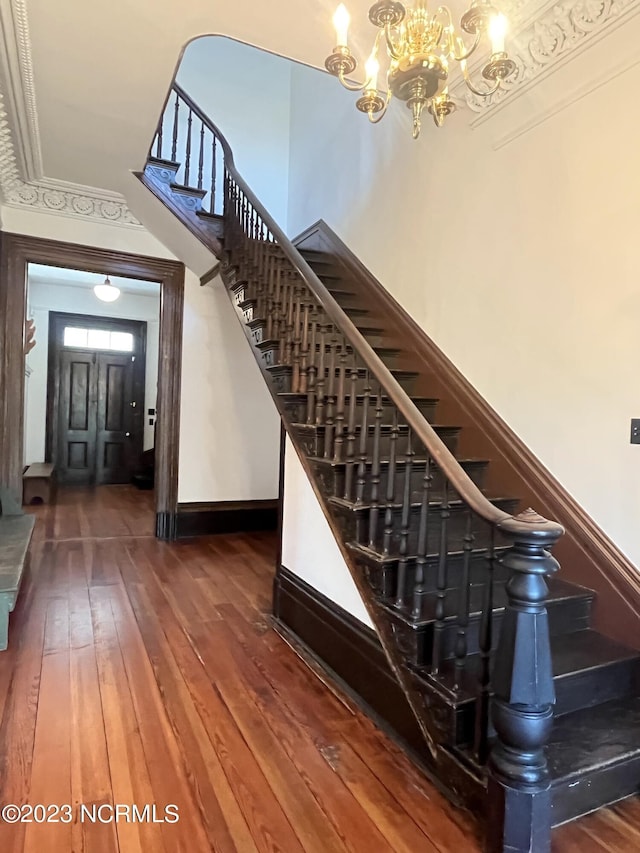 stairway featuring wood-type flooring and a notable chandelier