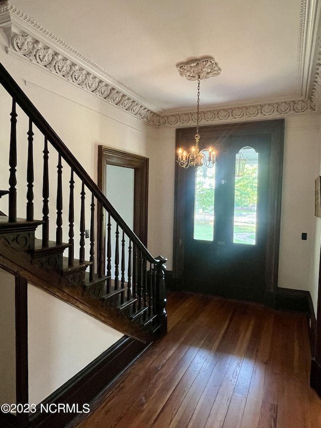 entrance foyer featuring crown molding, dark hardwood / wood-style floors, and a notable chandelier