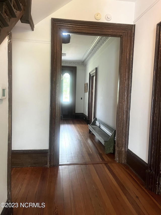 hallway with dark wood-type flooring and ornamental molding