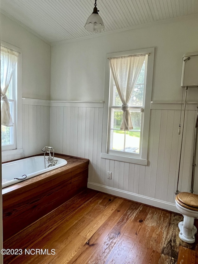 bathroom with hardwood / wood-style flooring, a tub to relax in, and toilet