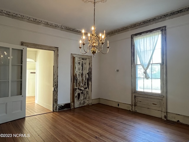 unfurnished dining area featuring a notable chandelier, a wealth of natural light, and wood-type flooring