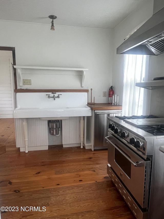 kitchen featuring wall chimney exhaust hood, appliances with stainless steel finishes, and dark hardwood / wood-style flooring