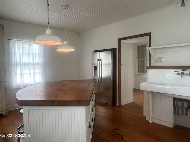 kitchen with pendant lighting, stainless steel fridge, dark wood-type flooring, white cabinets, and wood counters