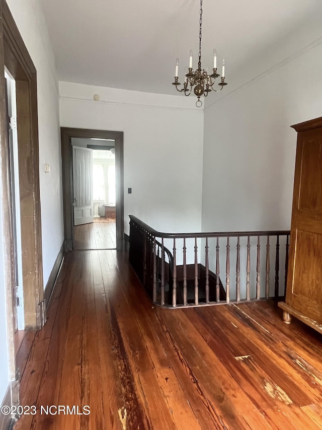 hall featuring dark wood-type flooring and a notable chandelier