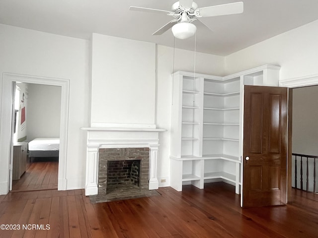 unfurnished living room featuring a tiled fireplace, ceiling fan, and dark hardwood / wood-style flooring