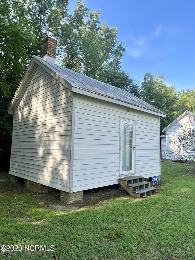 back of house with an outdoor structure and a lawn