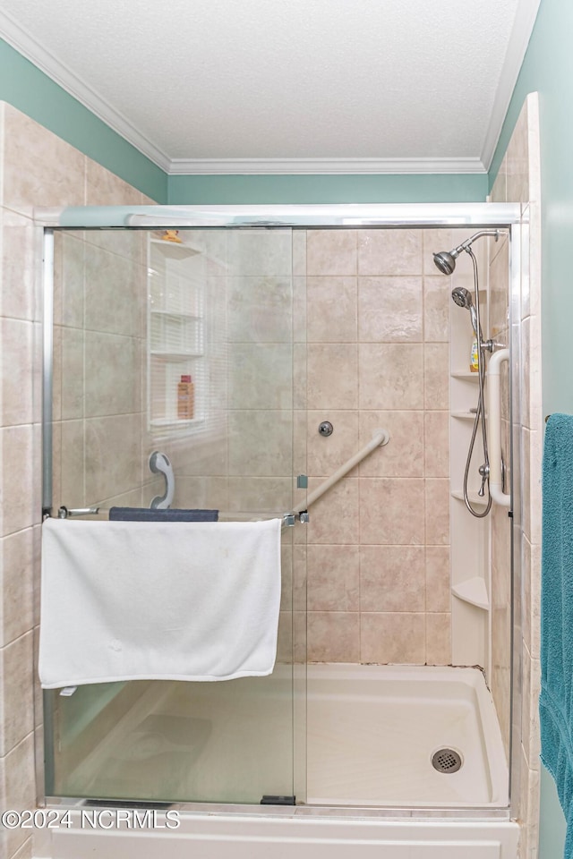 bathroom with a shower with door, ornamental molding, and a textured ceiling