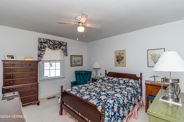 bedroom featuring ceiling fan, light colored carpet, and a textured ceiling