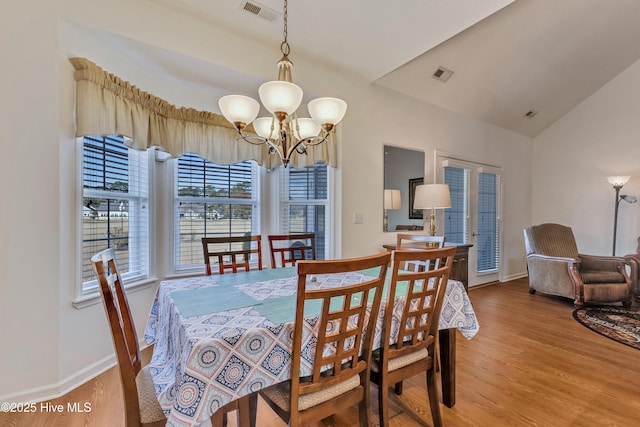 dining space with wood-type flooring, a chandelier, and vaulted ceiling