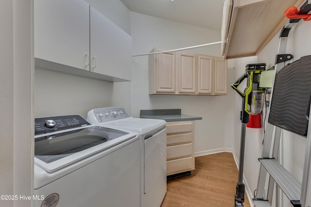 washroom featuring cabinets, separate washer and dryer, and light hardwood / wood-style flooring