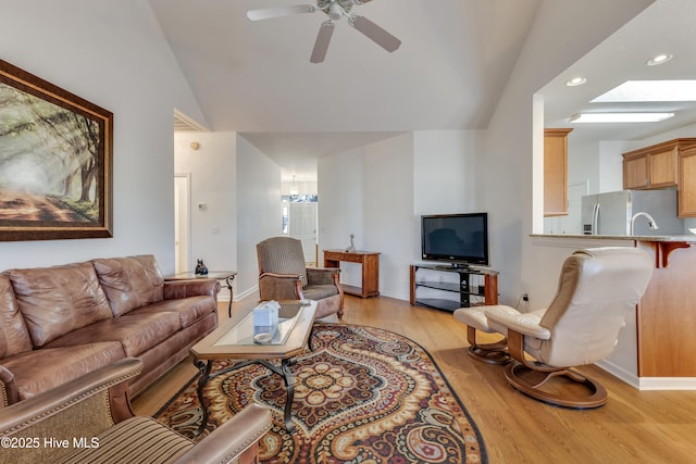 living room with ceiling fan, lofted ceiling, and light wood-type flooring