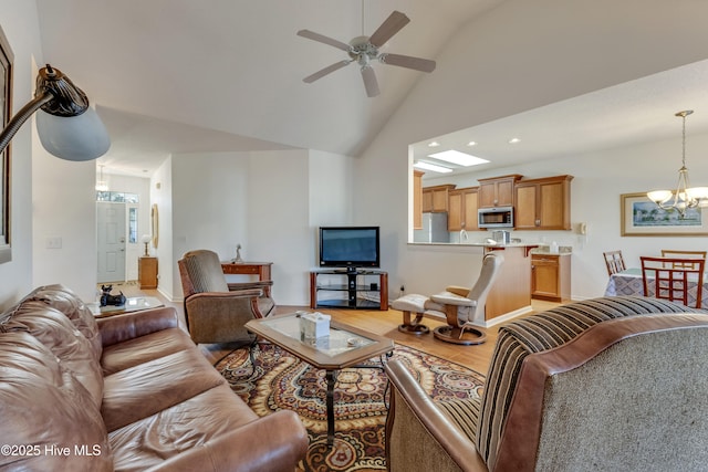 living room with ceiling fan with notable chandelier, high vaulted ceiling, and light wood-type flooring