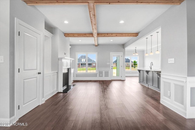 unfurnished living room featuring dark hardwood / wood-style floors, sink, and beam ceiling