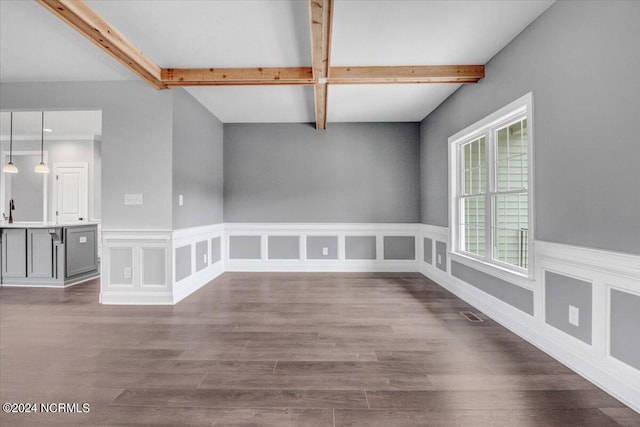 spare room featuring beam ceiling and wood-type flooring