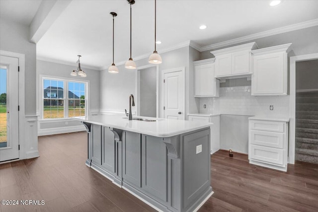 kitchen with a kitchen island with sink, sink, hanging light fixtures, and white cabinets