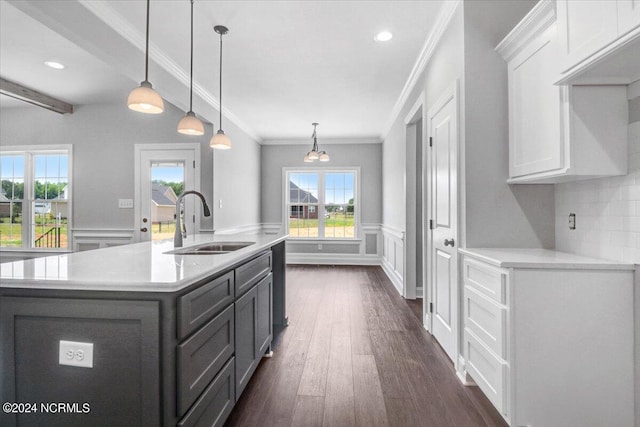 kitchen with sink, dark wood-type flooring, white cabinets, a center island with sink, and decorative light fixtures