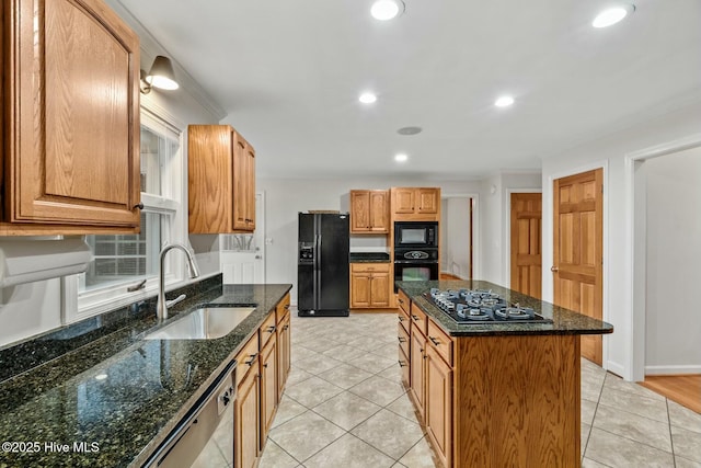 kitchen with sink, dark stone counters, a center island, light tile patterned floors, and black appliances