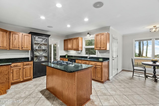 kitchen featuring sink, ornamental molding, a kitchen island, dark stone counters, and black appliances