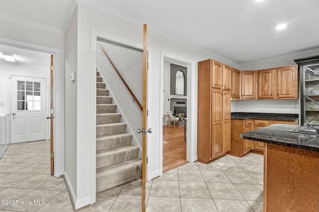 kitchen with light tile patterned flooring, dark stone counters, and crown molding