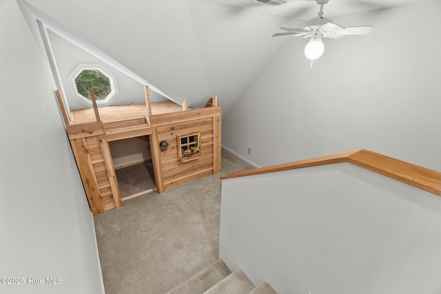 stairway featuring ceiling fan, carpet flooring, and vaulted ceiling