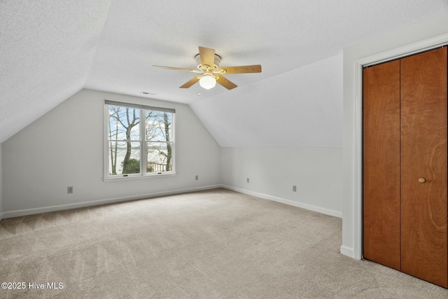 bonus room with light carpet, ceiling fan, lofted ceiling, and a textured ceiling