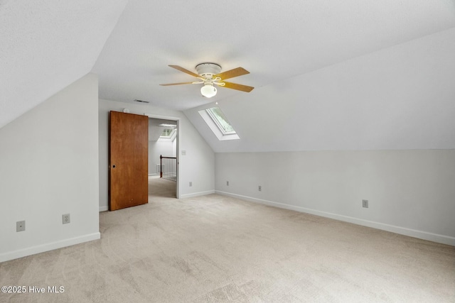 bonus room with light carpet, ceiling fan, and vaulted ceiling with skylight