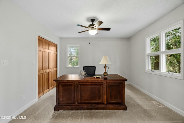 carpeted home office with a textured ceiling and ceiling fan