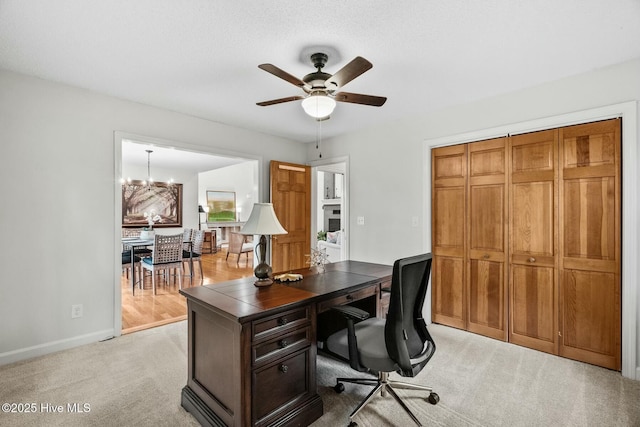 carpeted home office with ceiling fan with notable chandelier