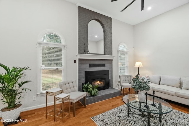 living room with wood-type flooring, a wealth of natural light, ceiling fan, and a fireplace