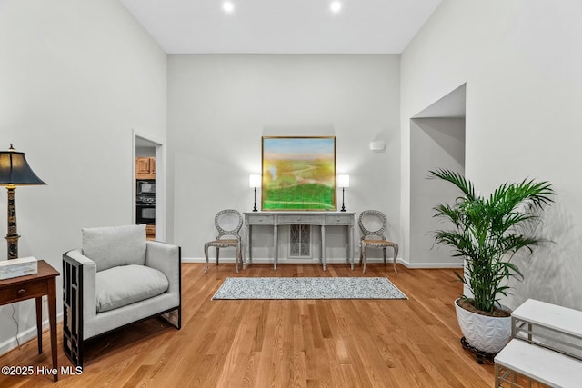 sitting room featuring a high ceiling and wood-type flooring